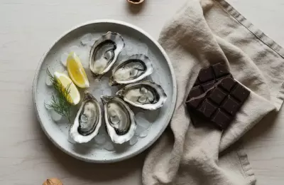 Table de fête épurée avec huîtres fraîches, chocolat noir et noix sur lin naturel.